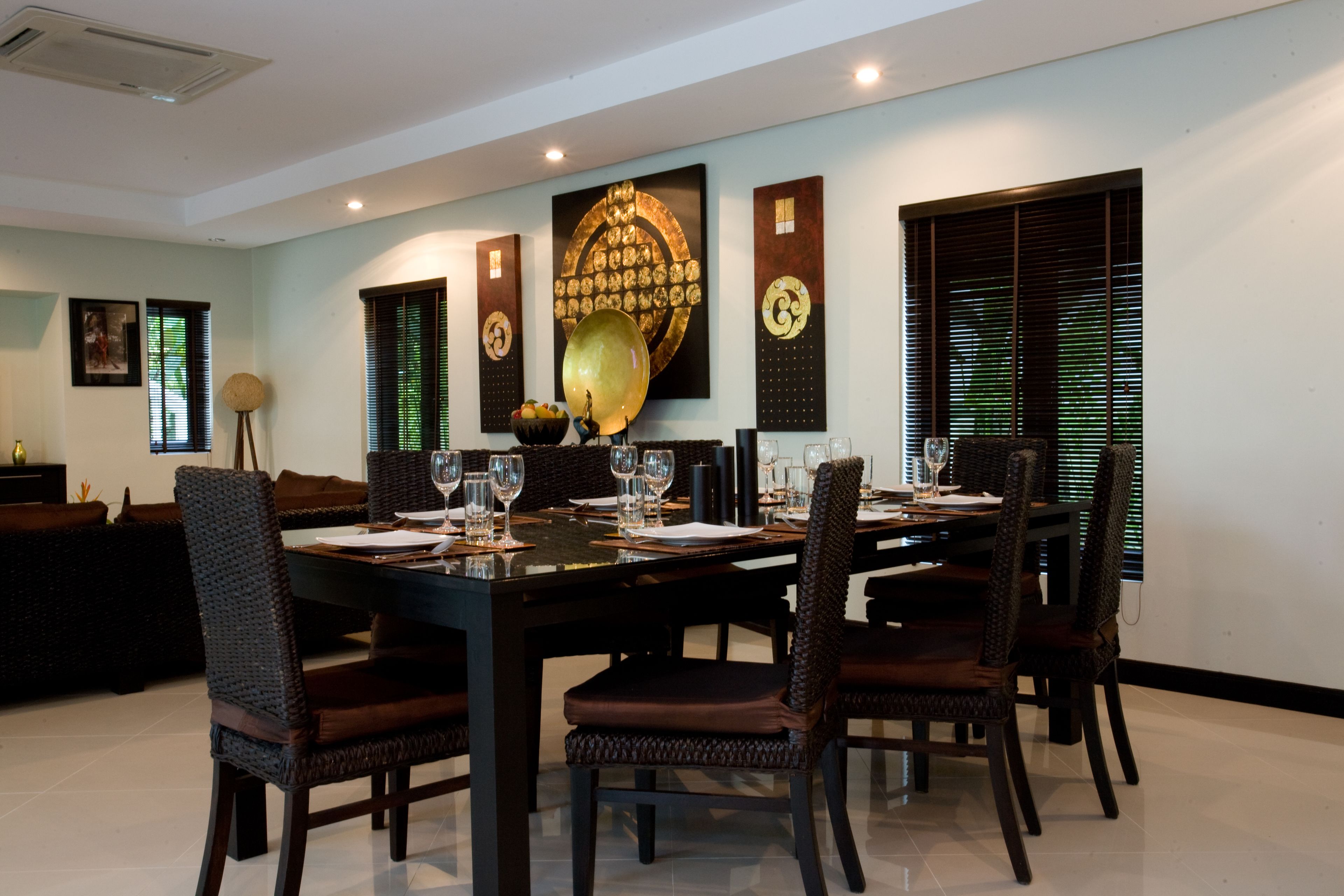 Un comedor con una mesa rectangular dispuesta para cuatro personas, rodeada de sillas de madera oscura.