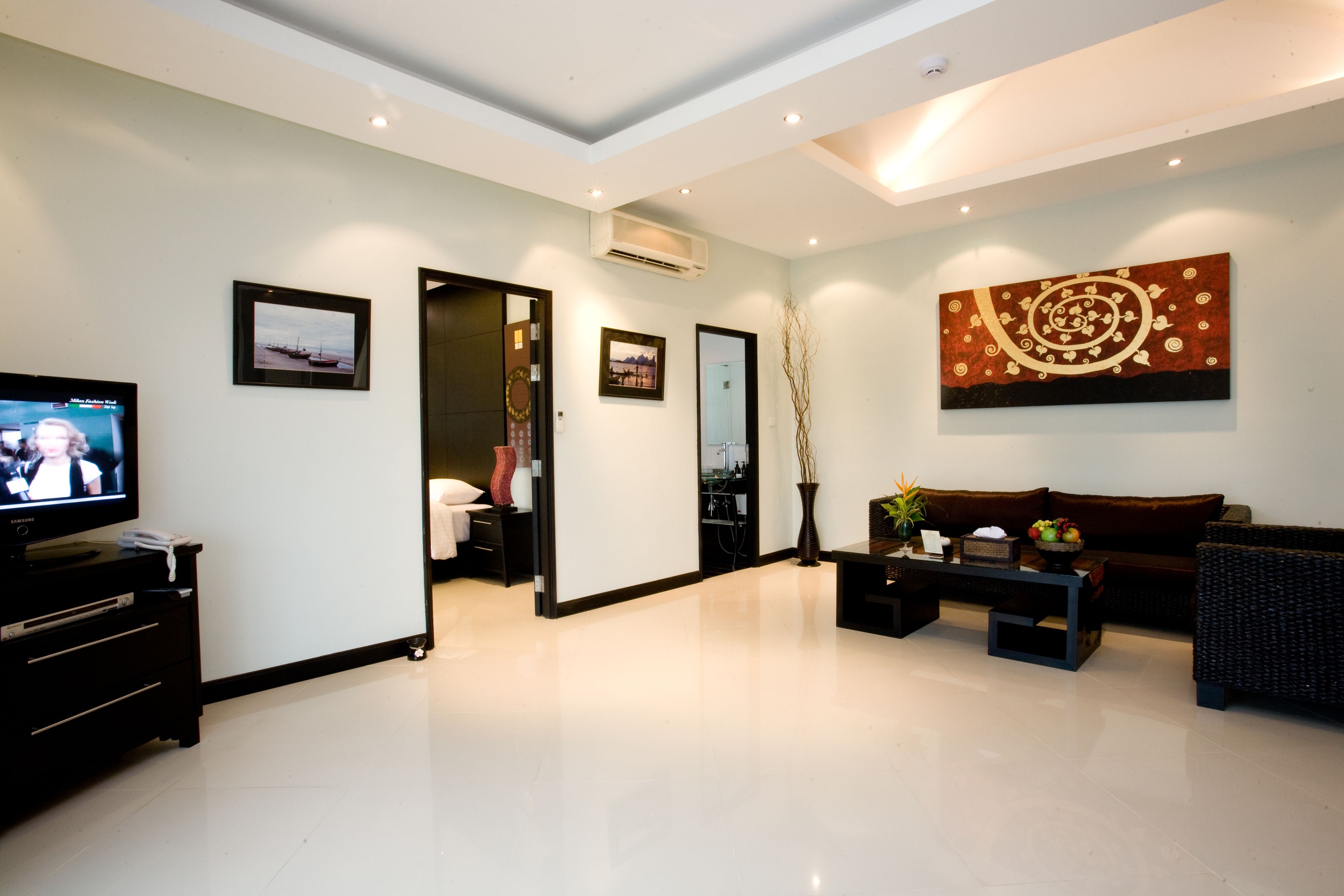 A modern living room with a flat-screen TV, a sofa, a coffee table, and a painting on the wall.
