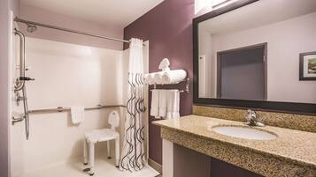 A bathroom with a shower, a sink, a mirror, and a towel rack.