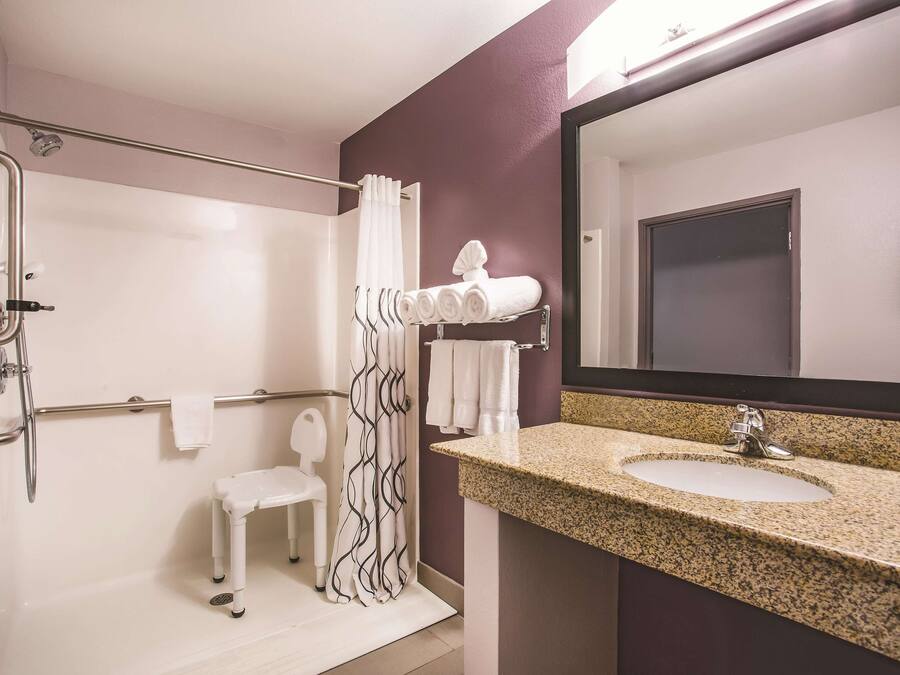 A bathroom with a shower, a sink, a mirror, and a towel rack.