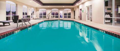 An indoor swimming pool with clear water, a lifeguard chair, and a pool ladder.