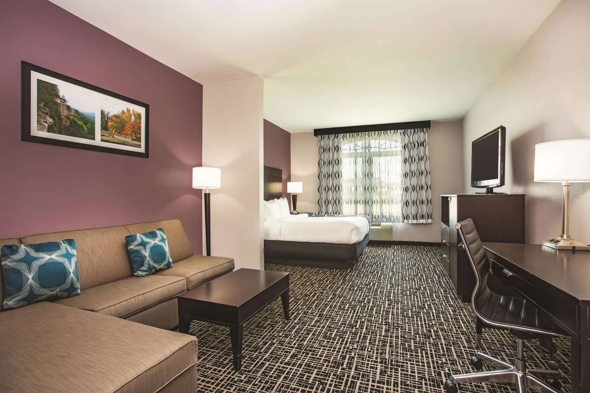 Habitación de hotel con sofá, cama, escritorio y televisor.