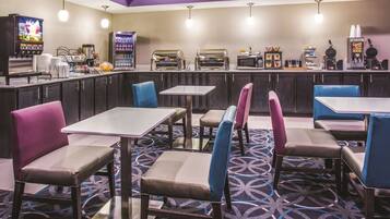 A restaurant with booths and tables, a counter with a coffee machine, and a TV screen.
