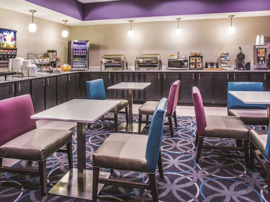 A restaurant with booths and tables, a counter with a coffee machine, and a TV screen.