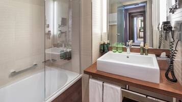 Une salle de bain moderne avec une douche à parois de verre, un lavabo blanc doté d’un plan de travail en bois et un miroir au-dessus du lavabo.