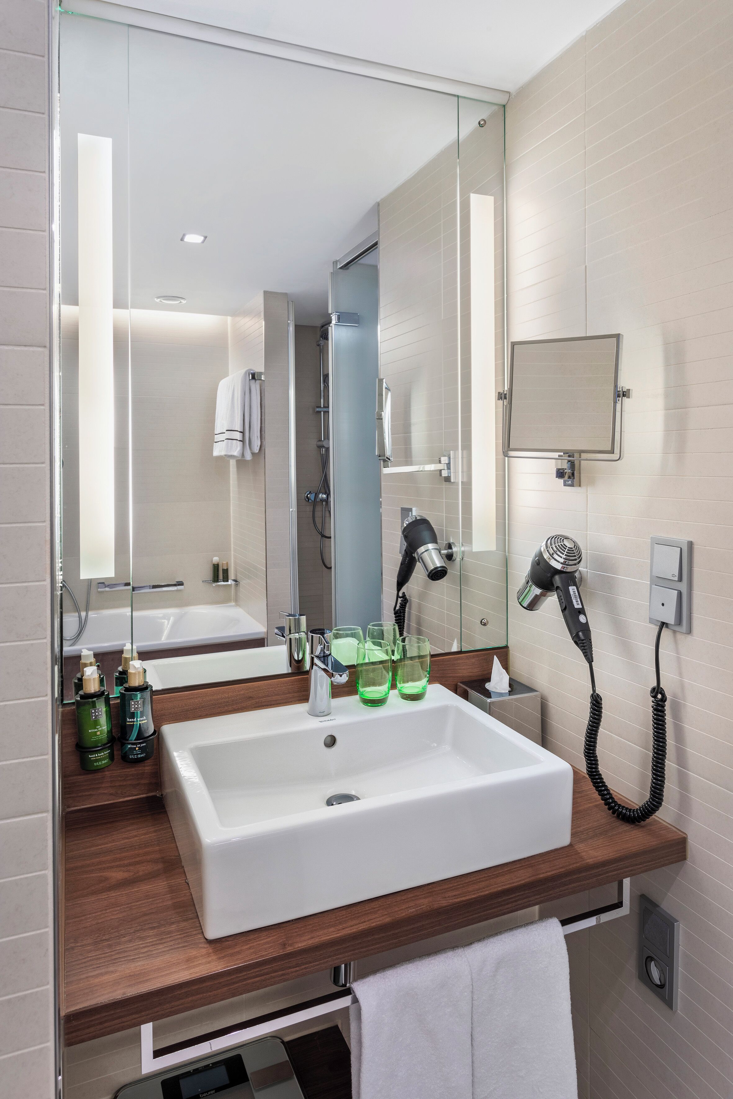 Un bagno moderno con uno specchio grande, un lavandino bianco e un asciugacapelli a parete.