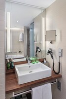 Un bagno moderno con uno specchio grande, un lavandino bianco e un asciugacapelli a parete.