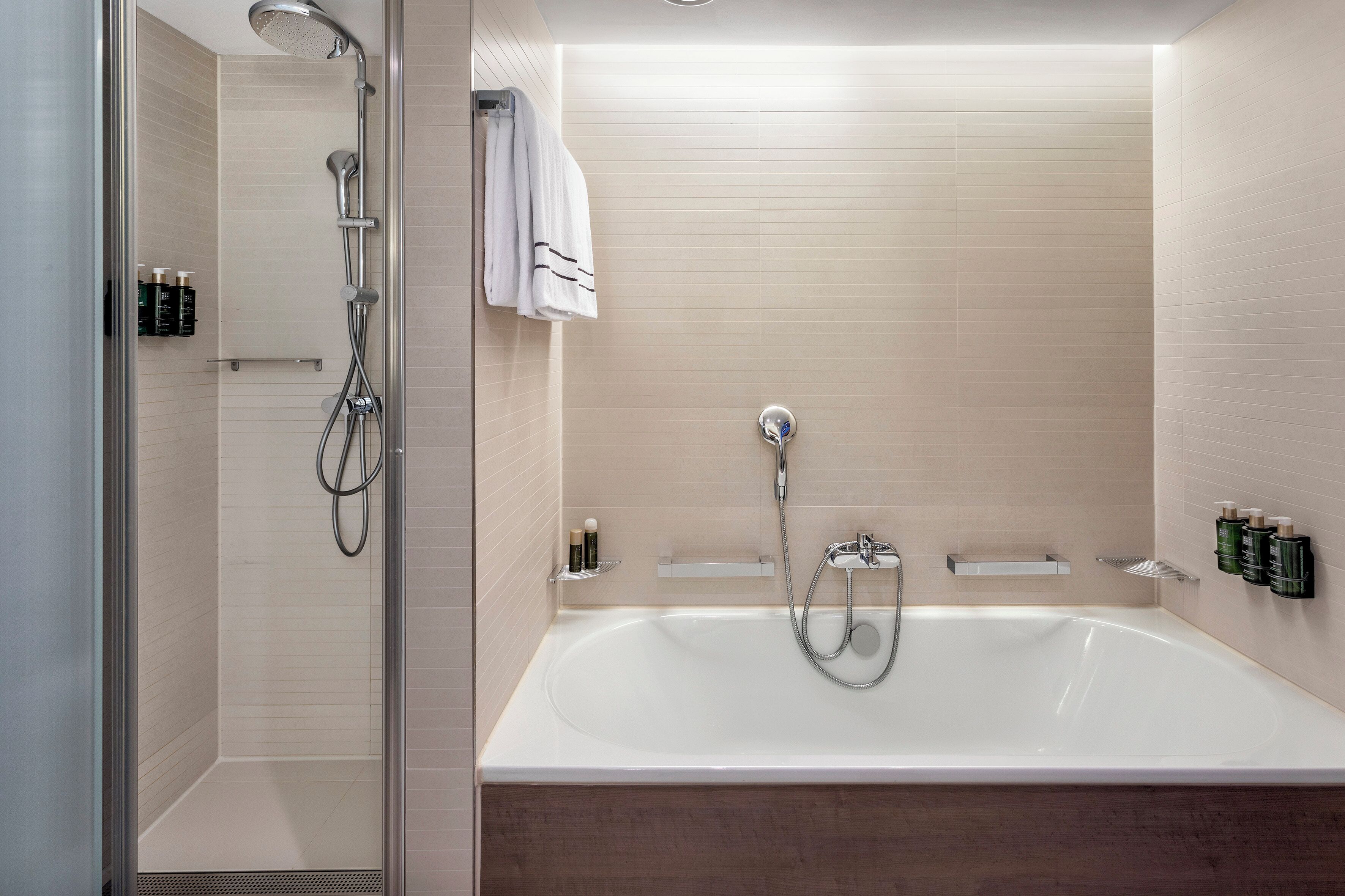 A modern bathroom with a glass-enclosed shower, a freestanding bathtub, and a towel rack.