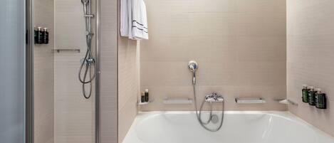 A modern bathroom with a glass-enclosed shower, a freestanding bathtub, and a towel rack.