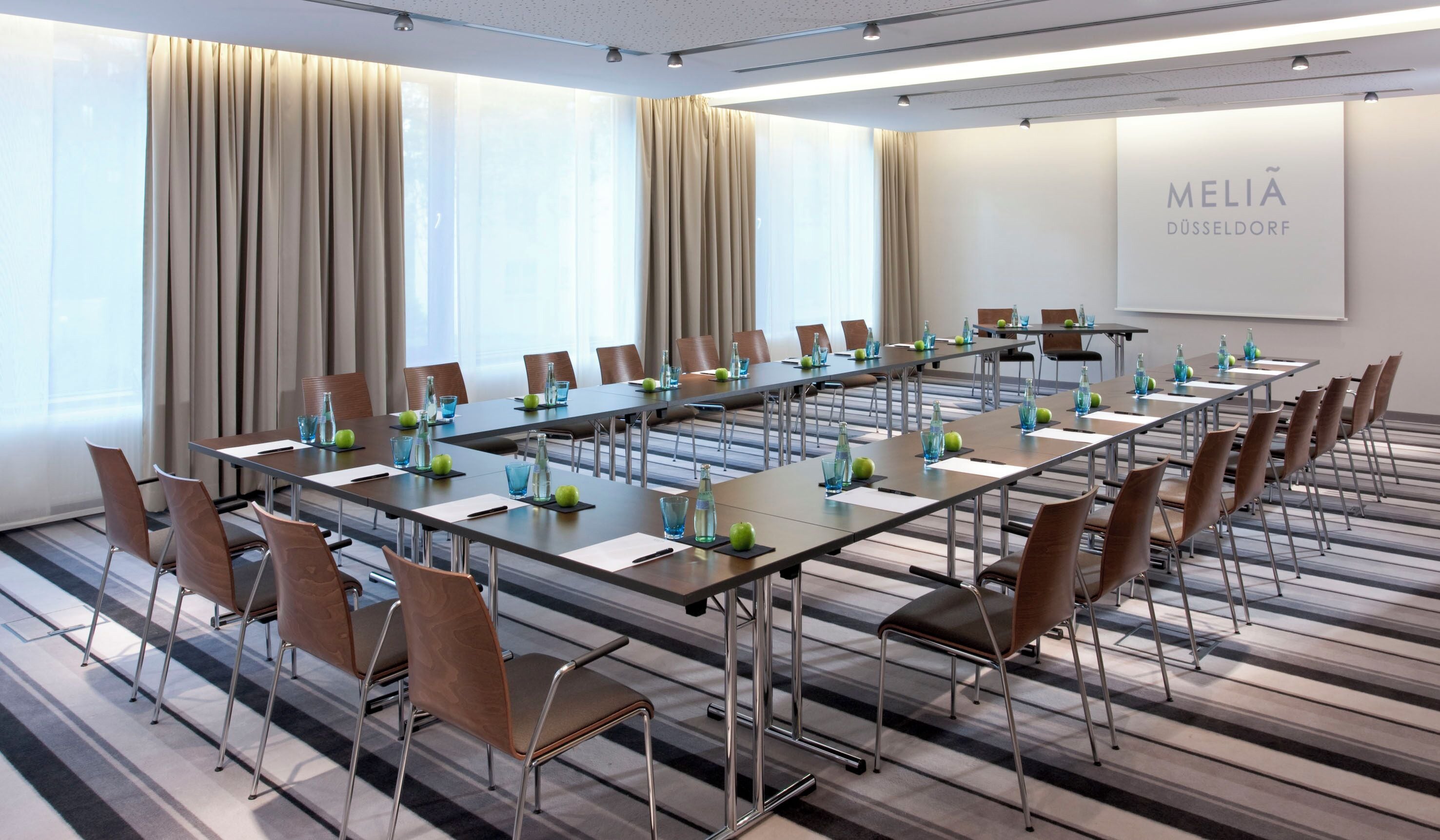 A conference room with long tables, chairs, and water bottles.