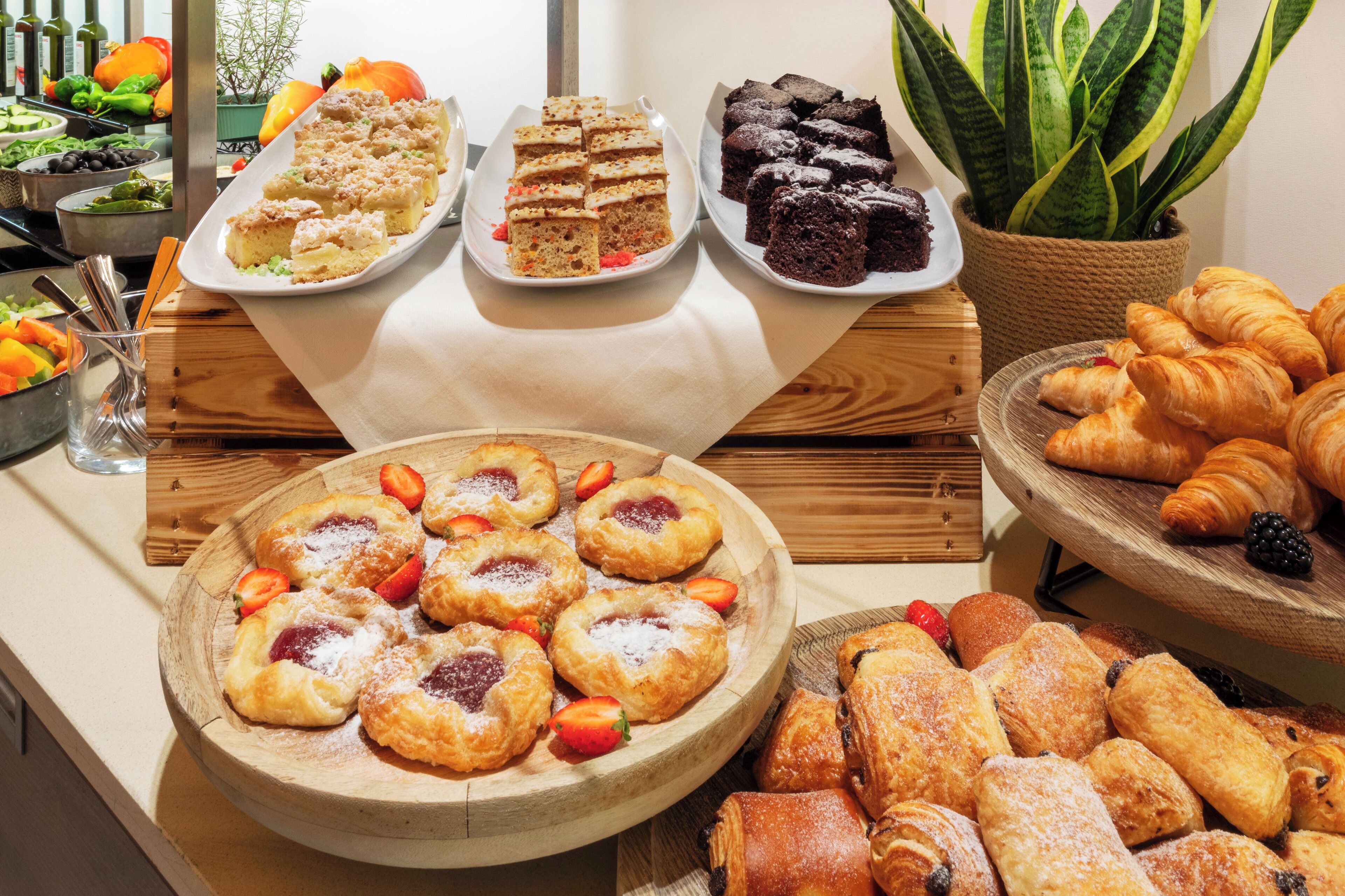A buffet with various pastries and desserts, including cakes, brownies, and croissants.
