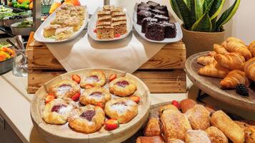 A buffet with various pastries and desserts, including cakes, brownies, and croissants.