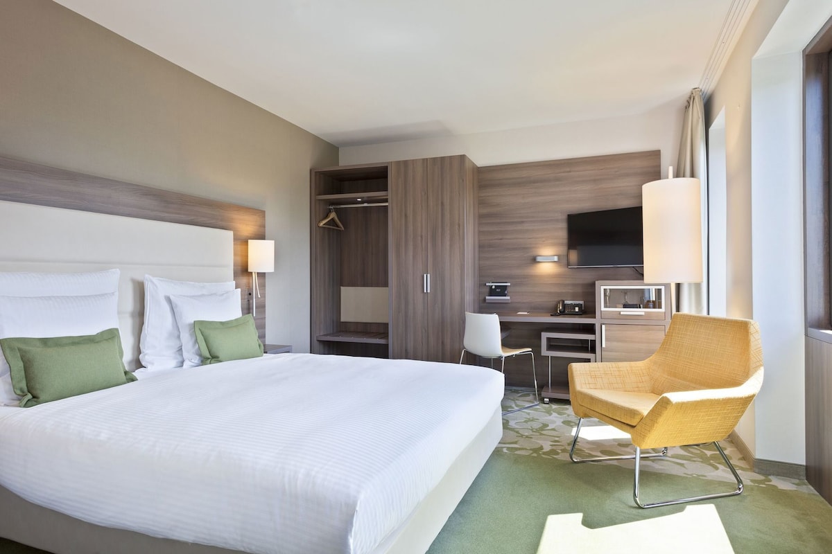 Une chambre d’hôtel avec un grand lit, un bureau, une chaise, une télévision et une armoire.