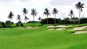 A golf course with sand bunkers and palm trees. - Microtel by Wyndham Eagle Ridge (General Trias)