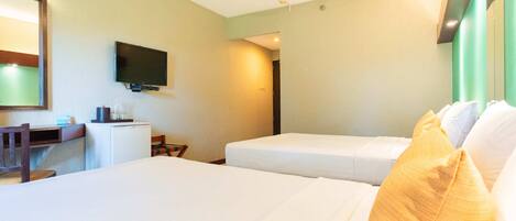 A hotel room with two beds, a desk, a television, and a mirror.