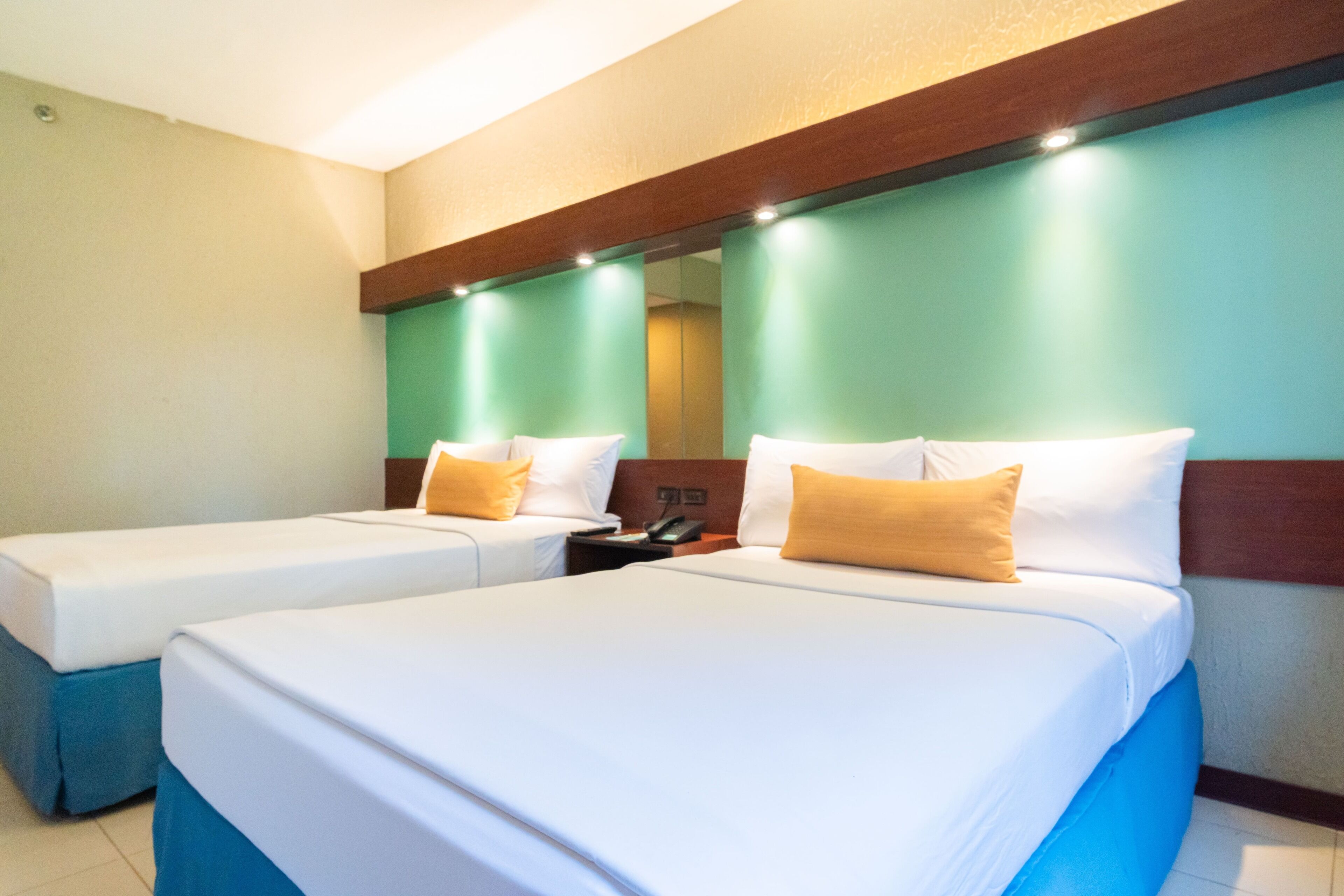 A hotel room with two beds, a mirror, and a nightstand with a phone.