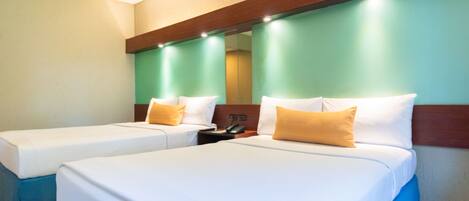 A hotel room with two beds, a mirror, and a nightstand with a phone.