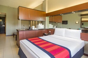 A hotel room with a large bed, a wooden desk with a coffee maker, a telephone, and a mirror. - Microtel by Wyndham Eagle Ridge (General Trias)