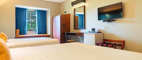 A hotel room with two beds, a desk, a chair, a television, and a window with curtains.
