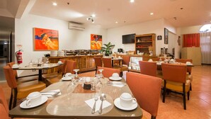 A restaurant with tables set for dining, a buffet area, and a reception desk. - Microtel by Wyndham Eagle Ridge (General Trias)