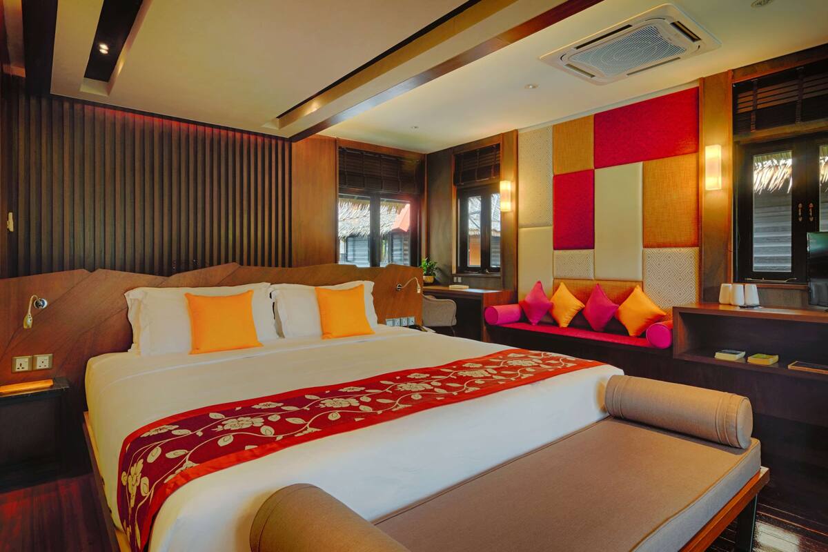 A hotel room with a large bed, a desk with a chair, and a sofa.