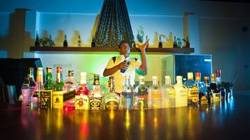 Un espace bar avec différentes bouteilles d’alcool et une personne tenant une bouteille.