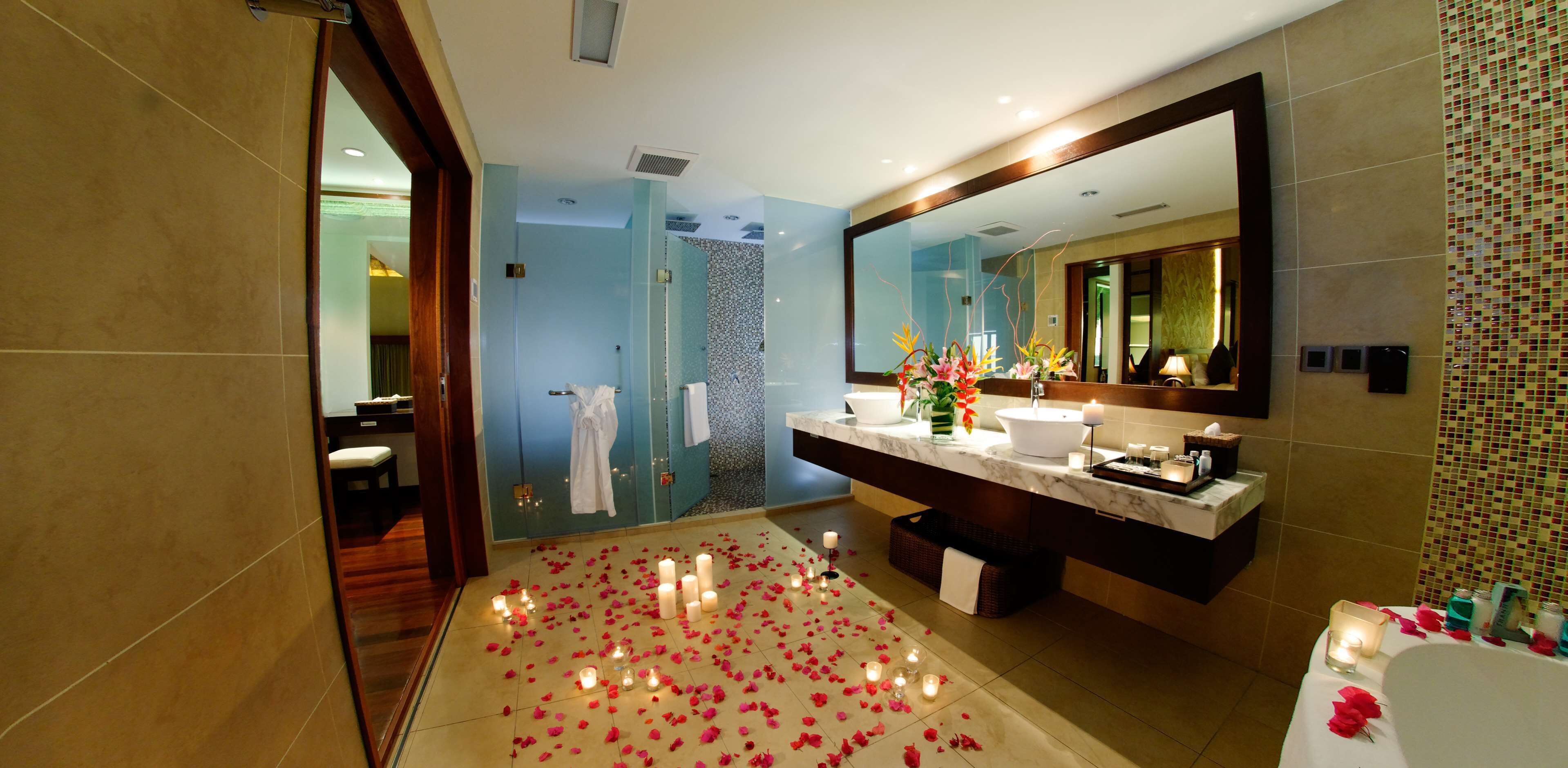Un baño moderno con un espejo grande, encimera de mármol y cabina de ducha.