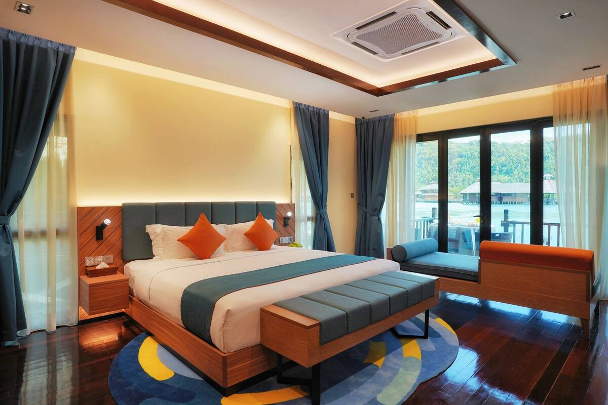 A modern hotel room with a large bed, a seating area, and a view of the outdoors.