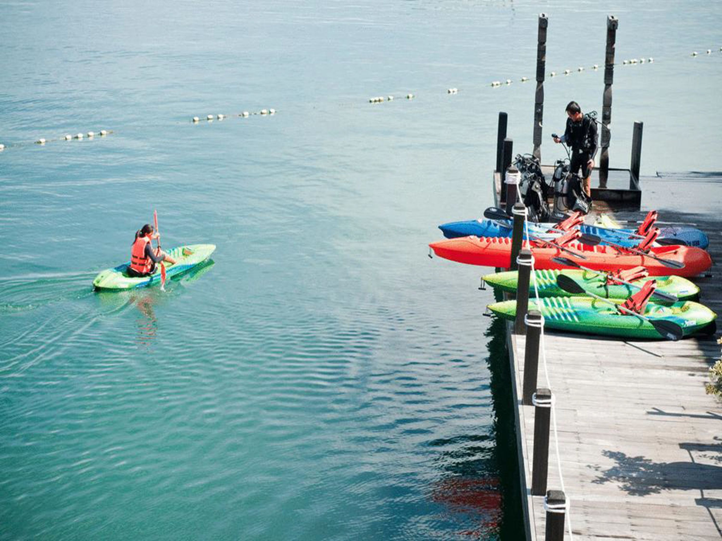 A calm lake with kayaks docked at a wooden pier.
