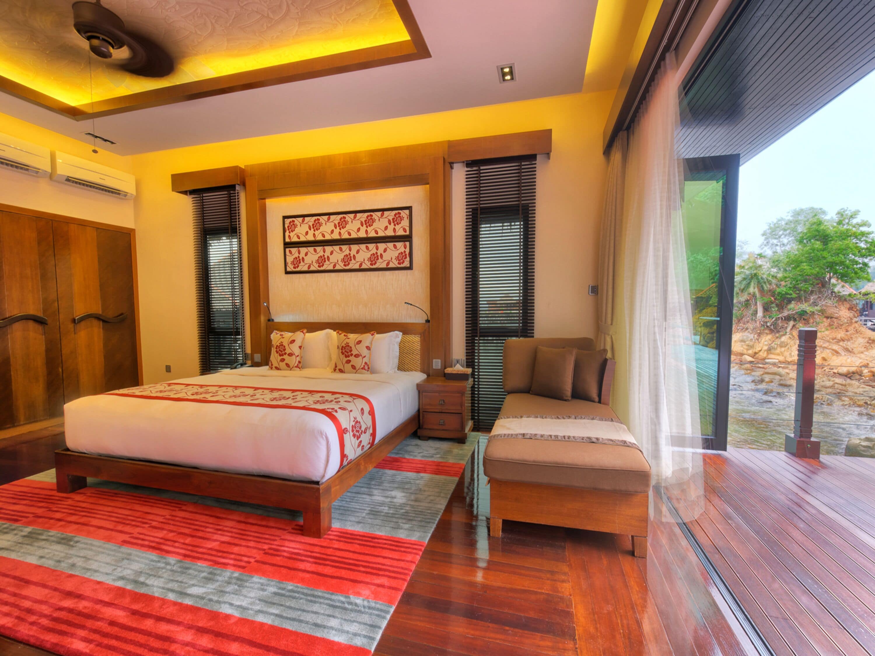 Un dormitorio moderno con una cama grande, un banco de madera y vistas al exterior.