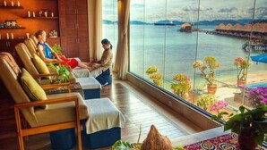 A room with a view of the sea, featuring a sofa, a table with a coconut and snacks, and a potted plant. - Gayana Marine Resort (Gaya Island)