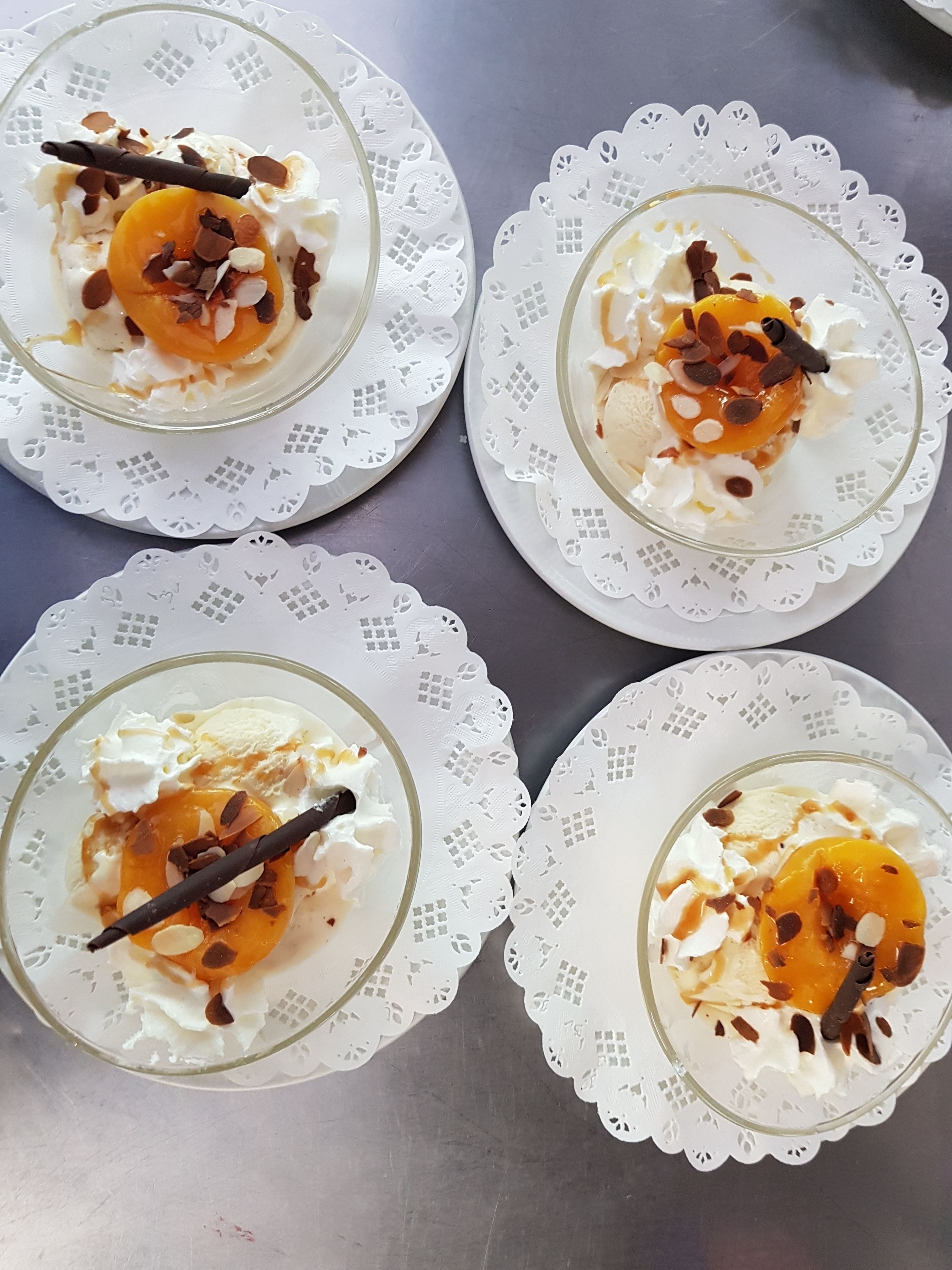 Four glass dessert bowls on white doilies.