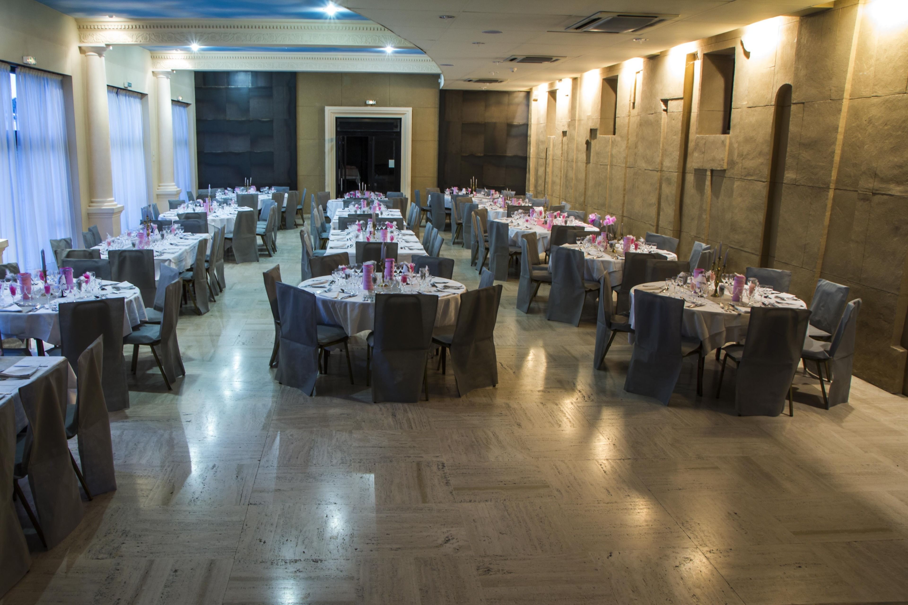 A banquet hall with round tables, chairs, and tables set for a formal event.