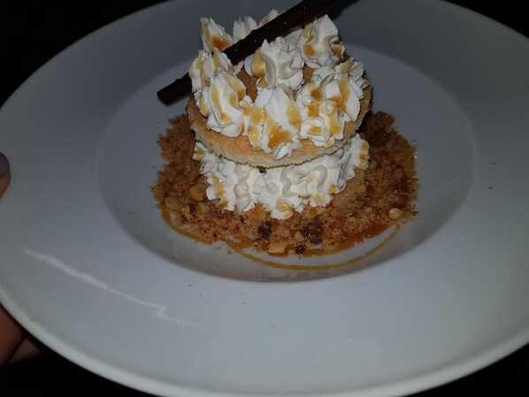 A dessert on a white plate with whipped cream and caramel sauce.