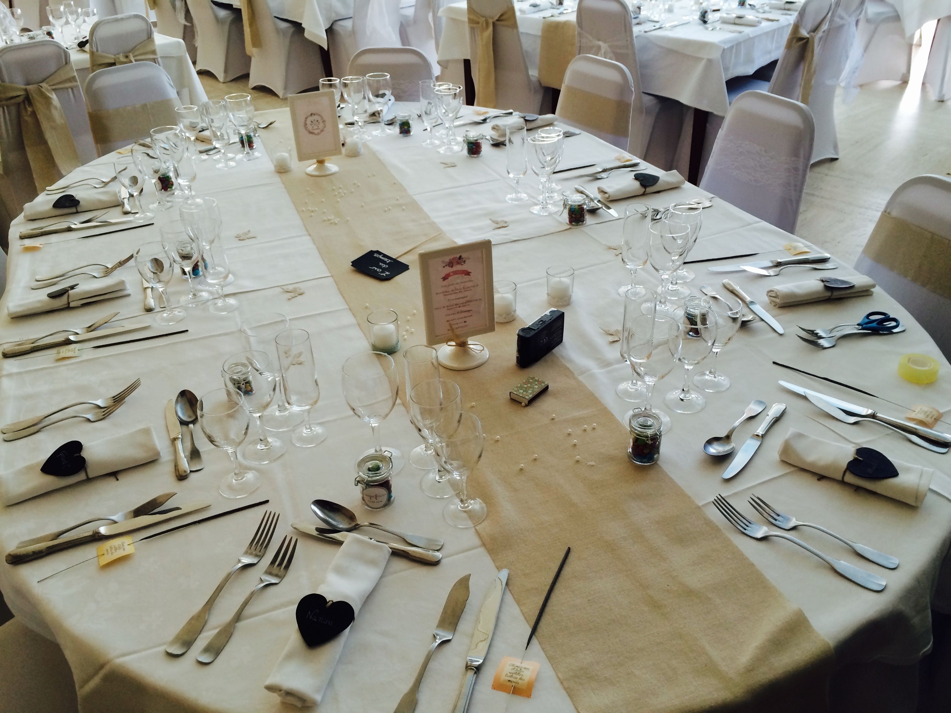 Een feestzaal met ronde tafels voor een formeel evenement, met witte tafelkleden, netjes geplaatste bestek en wijnglazen.