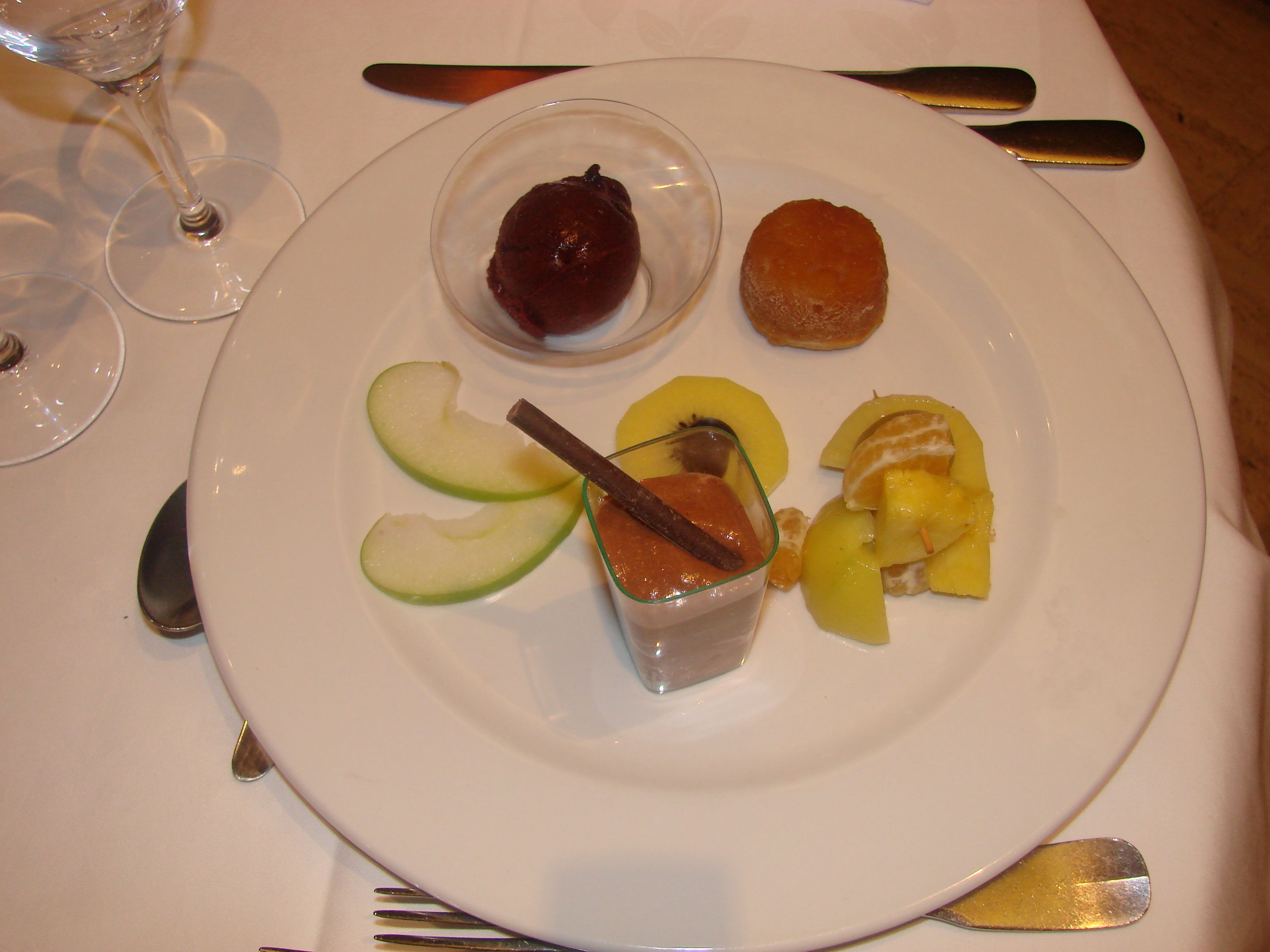 A plate with sliced apples, a small glass container with a brown substance, and a pastry.