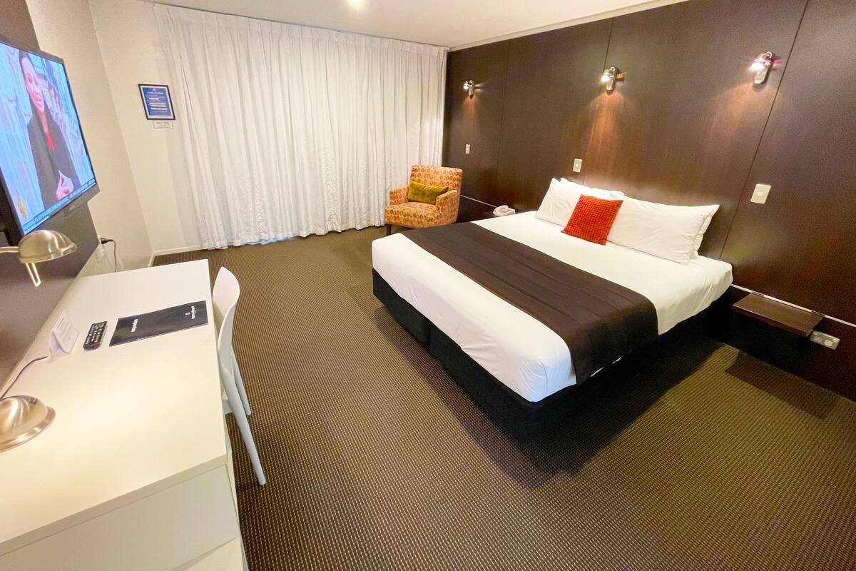 Une chambre d’hôtel avec un grand lit, un bureau avec un ordinateur, une chaise et un téléviseur.