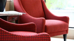 Un fauteuil rouge à motifs et un pouf assorti se trouvent dans une pièce dotée d’une fenêtre.