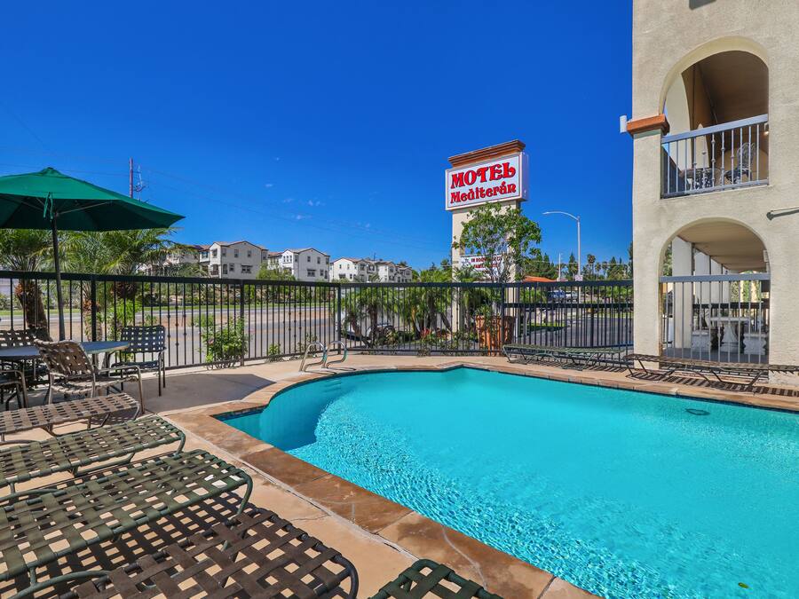 A pool area with lounge chairs and a sign for 'Motel Mediterran'.