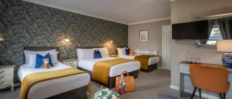 A hotel room with two beds, a desk, a chair, a TV, and a stone-patterned wall.