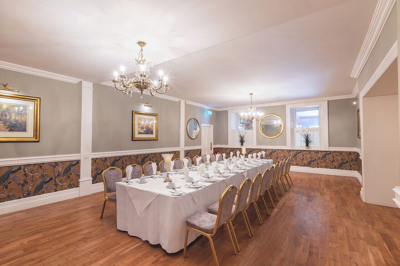 A long dining table set for a formal event, with chairs and a chandelier.