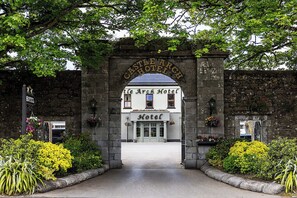 L’entrée de l’hôtel Castle Arch se distingue par son arc en pierre, sa façade blanche et une enseigne placée au-dessus de l’entrée.