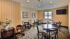 A conference room with striped walls, ceiling lights, a flat-screen TV, and a patterned carpet. - Cobblestone Inn & Suites - Brillion (Brillion)