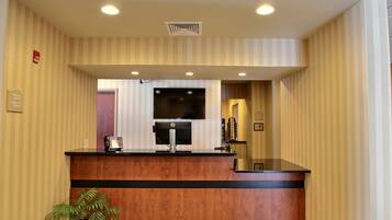 A reception desk with a flat-screen TV, a telephone, and a potted plant.