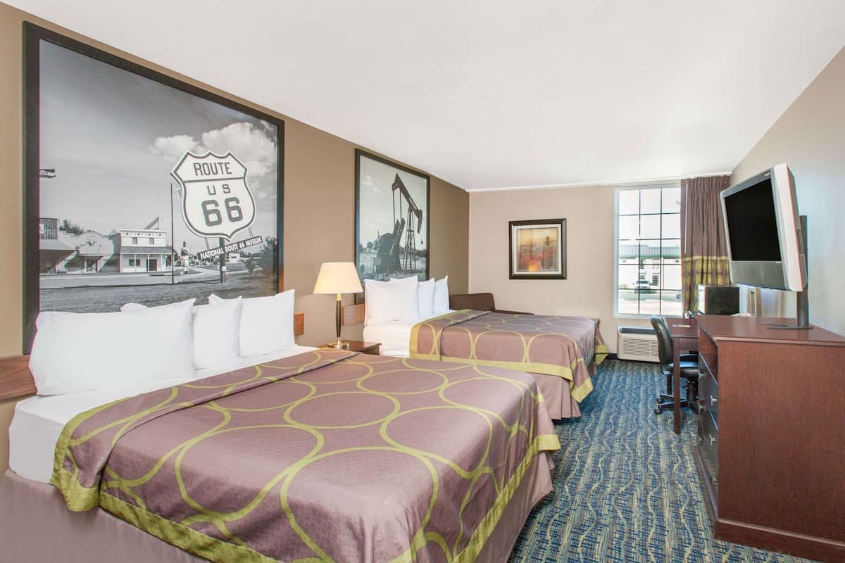 Ein Hotelzimmer mit zwei Betten, einem Schreibtisch, einem Fernseher und einer großen Route 66 Wandmalerei.
