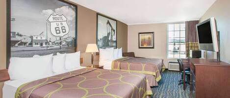 Habitación de hotel con dos camas, un escritorio, un televisor y obras de arte en las paredes.