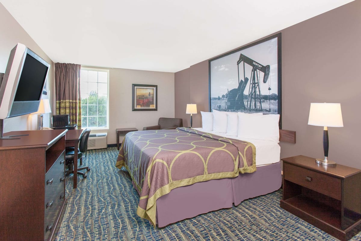 Ein Hotelzimmer mit Bett, Schreibtisch, Stuhl und Fernseher.