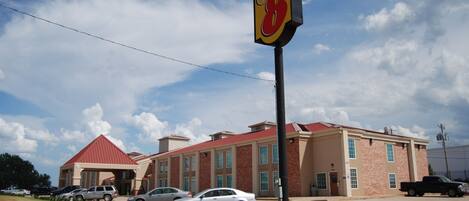 A hotel with a red roof, a Super 8 sign, and several parked cars in front.