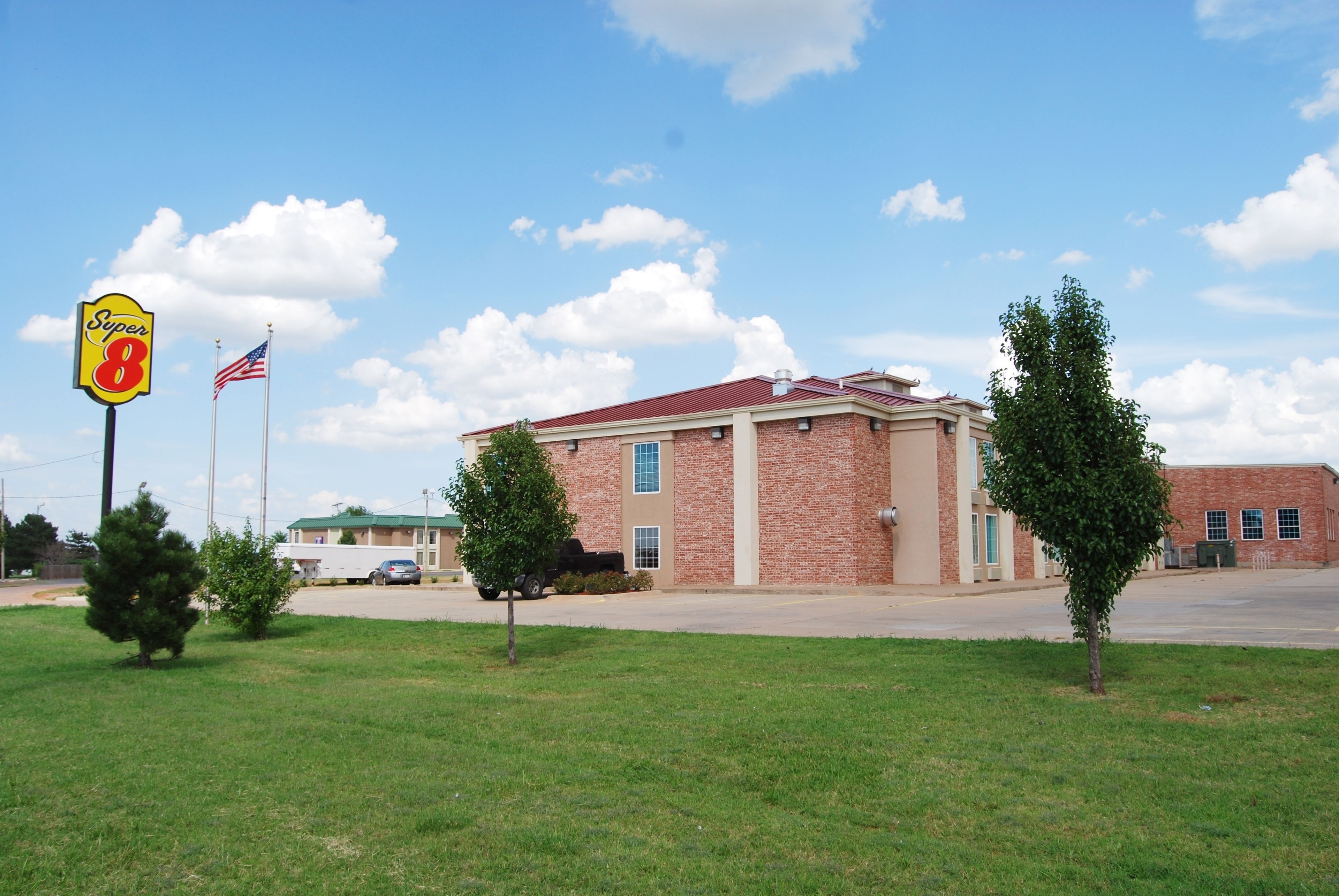 A Super 8 motel with a brick facade, two flagpoles, and a well-maintained lawn.