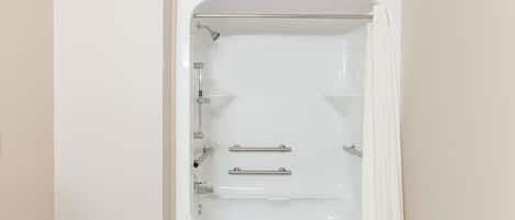Una bañera blanca con ducha, barras de apoyo y panel de control.